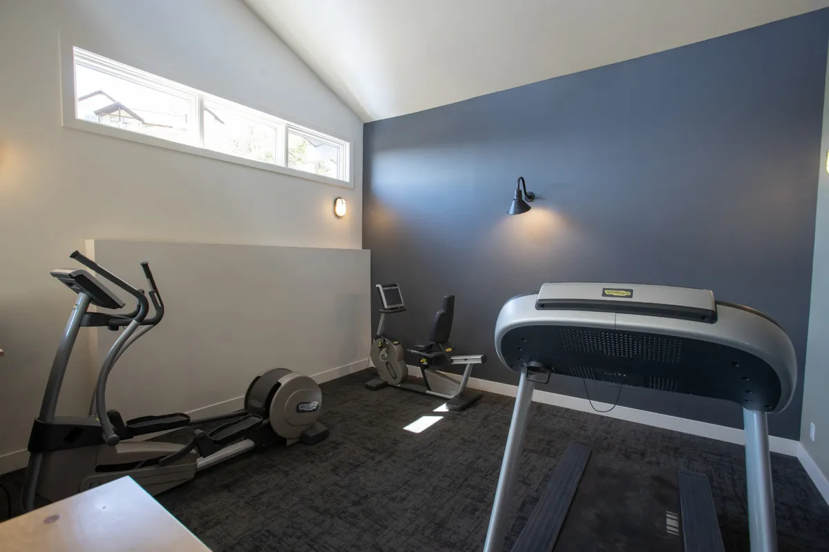 A well-equipped fitness center with a treadmill, elliptical machine, and exercise bike is shown. The space is bright and motivating, inviting guests to maintain their workout routines even while on vacation.