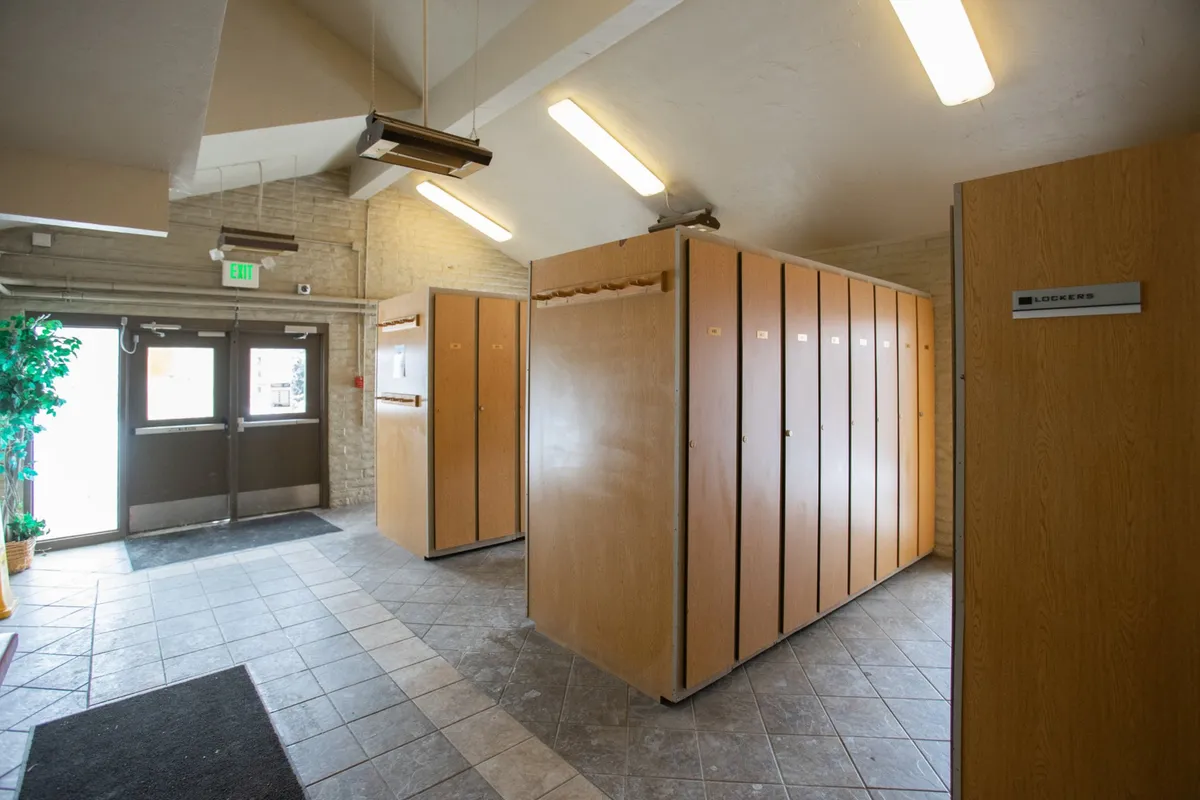 A functional and welcoming locker area is shown, featuring modern lockers, an entrance door, and a decorative plant. The setup suggests convenient storage for gear, such as skis and snowboards, making transitions between adventures seamless.