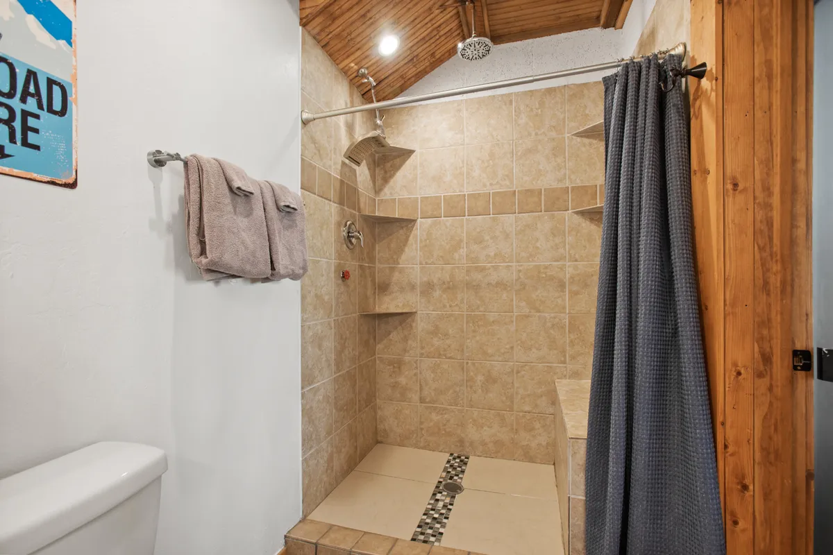 This calming bathroom image captures a modern shower area, towel rack, and decorative wall sign. The ambiance is soothing and spa-like, echoing the idea of a luxurious ensuite bath for personal rejuvenation.