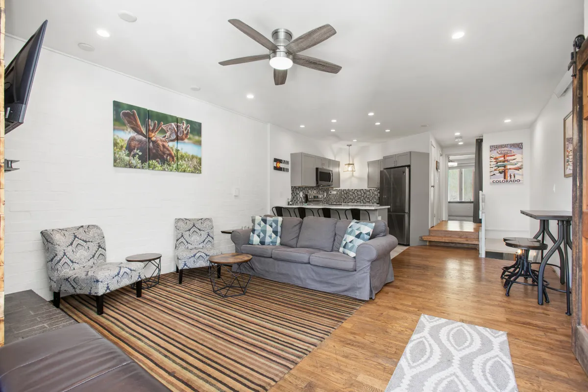 A cozy and inviting space with a sofa, wall art, and a wooden dining table with chairs. The arrangement hints at a space conducive to relaxing, playing board games, or gathering for group activities, aligning with the idea of après-ski fun and quality time together.